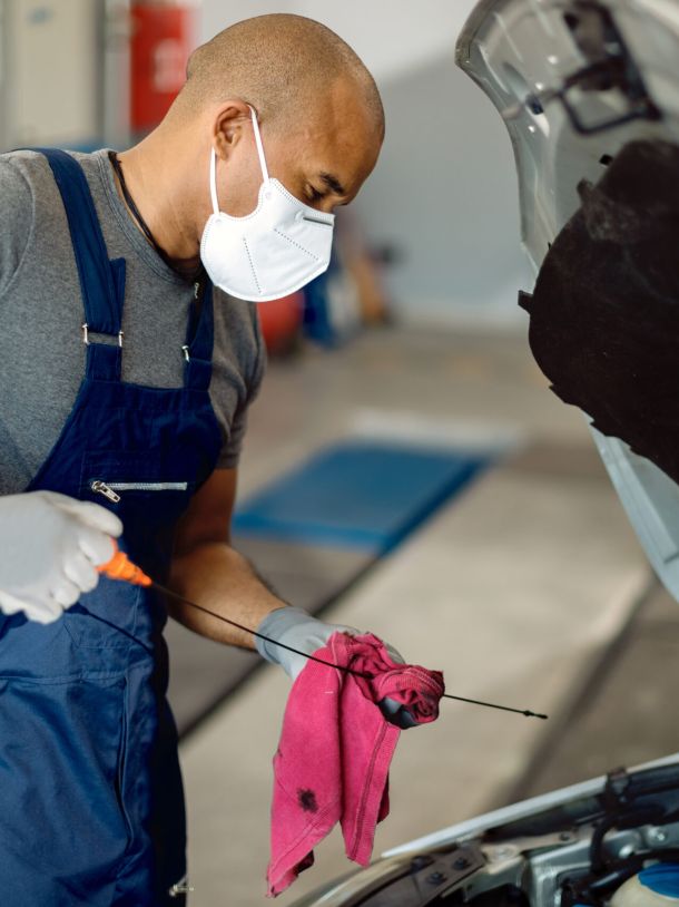 Service Tech Wearing Face Mask Completing Oil Level Check